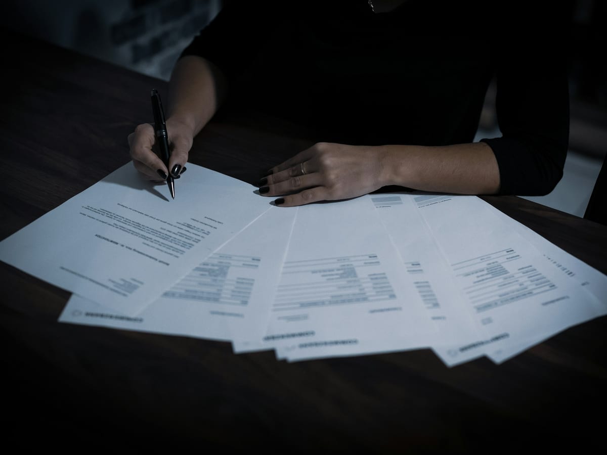 Signing a spread of documents at a desk