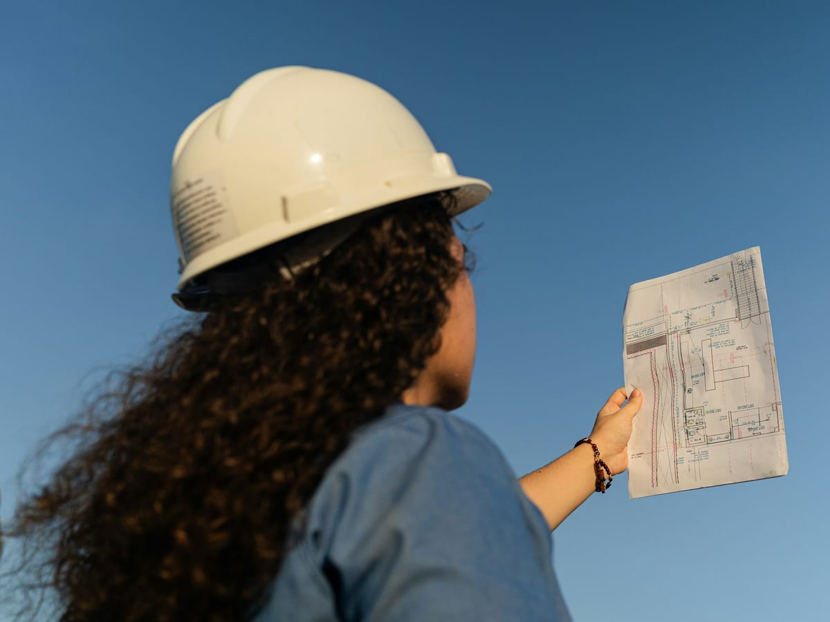Project manager in a hard hat checking a floor plan on site
