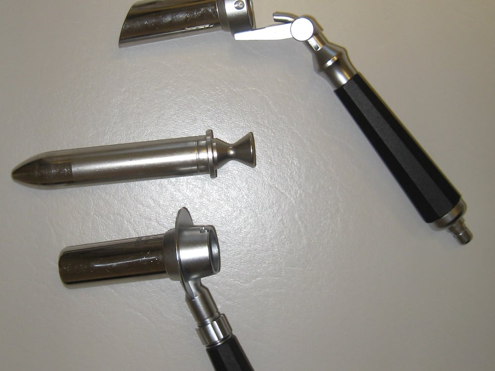Rigid stainless-steel endoscope sheaths and an obturator alongside a black instrument handle, arranged on a neutral surface