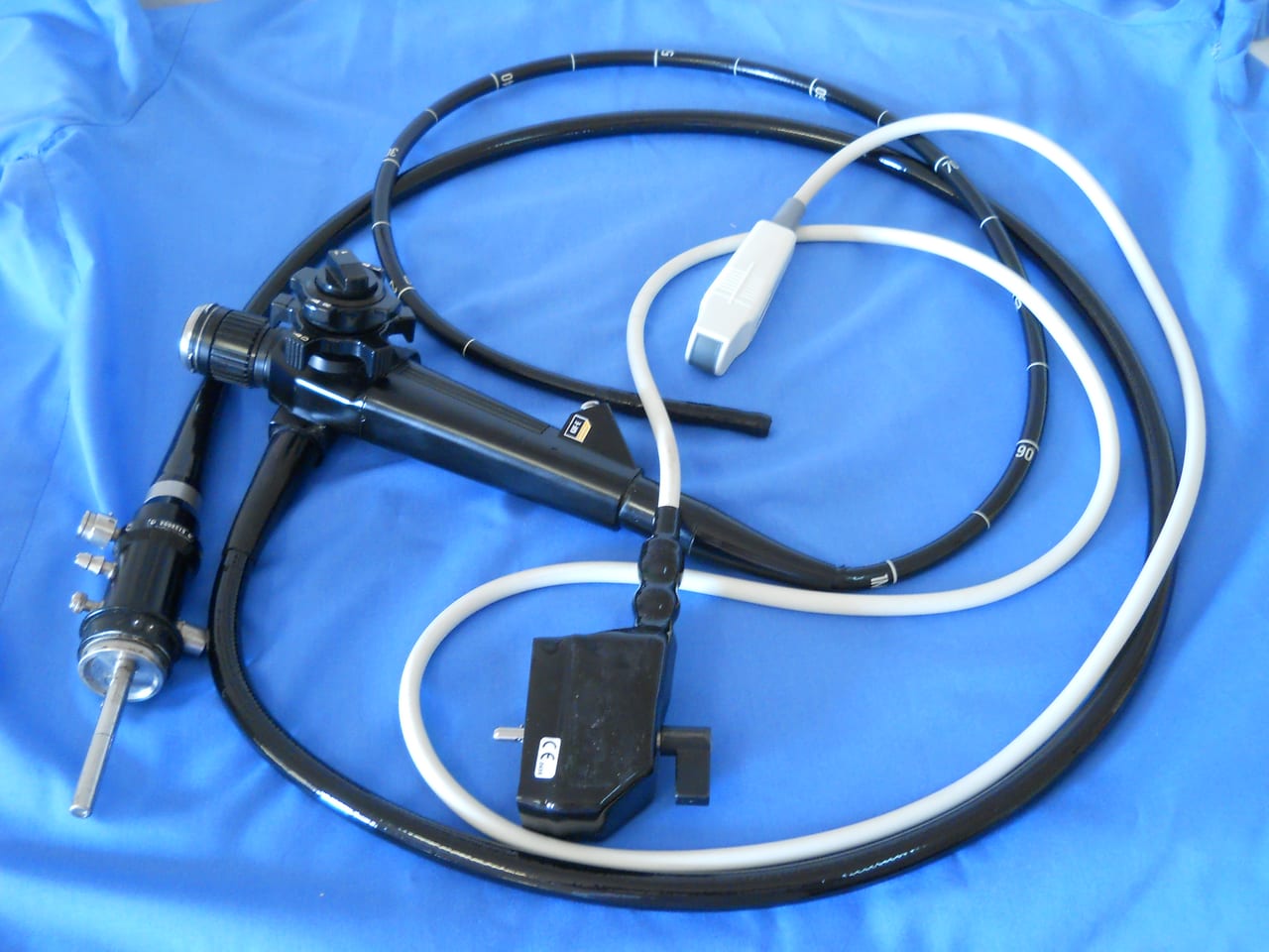 Flexible video endoscope with a coiled insertion tube and control handle laid out on a blue surgical drape