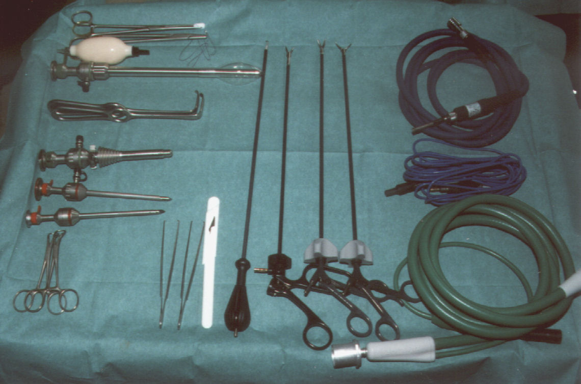 A set of used rigid endoscopic surgical equipment — rigid scopes, trocars and cannulas, coiled fiber-optic light cables, and hand instruments — laid out on a surgical drape