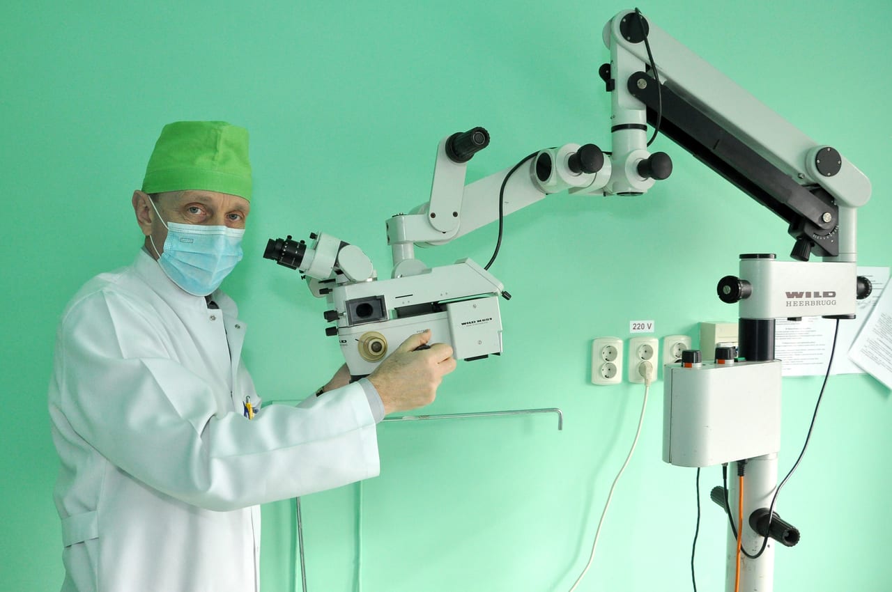 A Wild Heerbrugg (Leica) M651 surgical operating microscope on its floor-stand column, with binocular optics and an articulated support arm