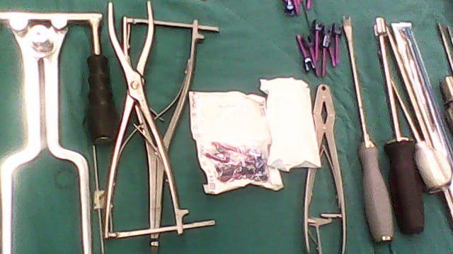 Laminectomy and spinal-fusion instrument set laid out on a surgical drape — a self-retaining retractor, distractors, bone forceps, drivers, and pedicle-screw caddies
