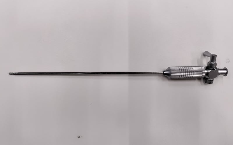 A used rigid rod-lens endoscope on an intake bench, showing the metal eyepiece, stopcock body, and straight shaft with light handling wear