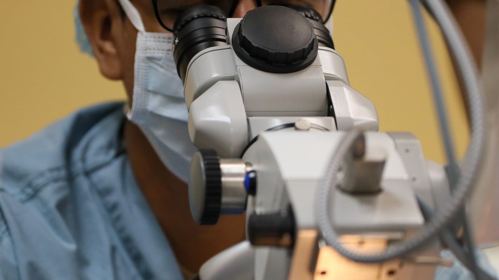Surgeon looking through the oculars of an articulated operating microscope