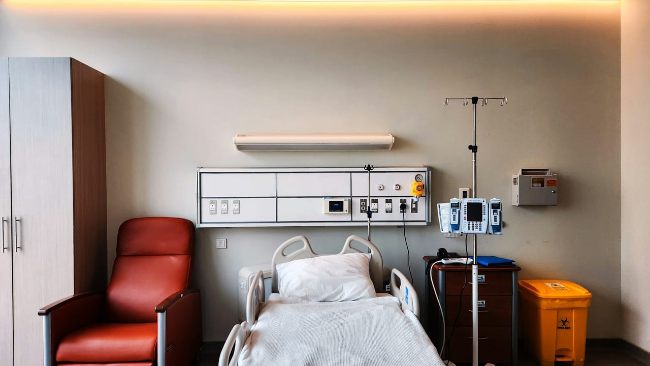 A hospital ward with beds and clinical equipment being cleared during a facility transition.