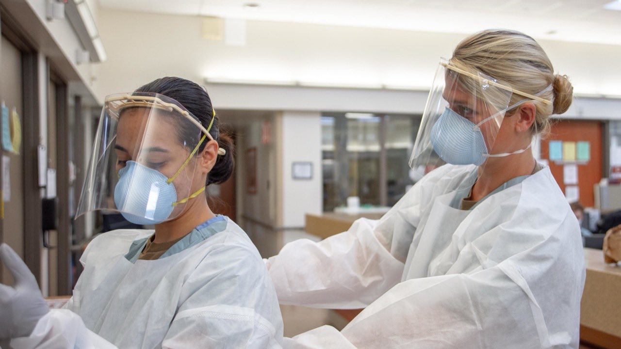 Clinical staff in full personal protective equipment following safe-handling protocols.