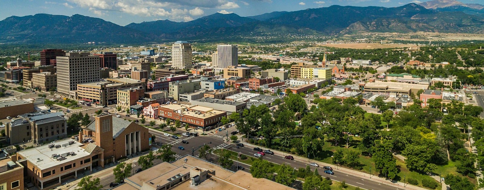 Aerial view of downtown Colorado Springs and Acacia Park, with Pikes Peak and the Front Range behind