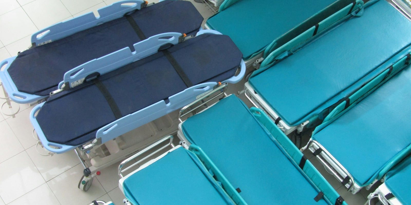 Rows of empty stretchers and transport trolleys parked side by side, seen from above