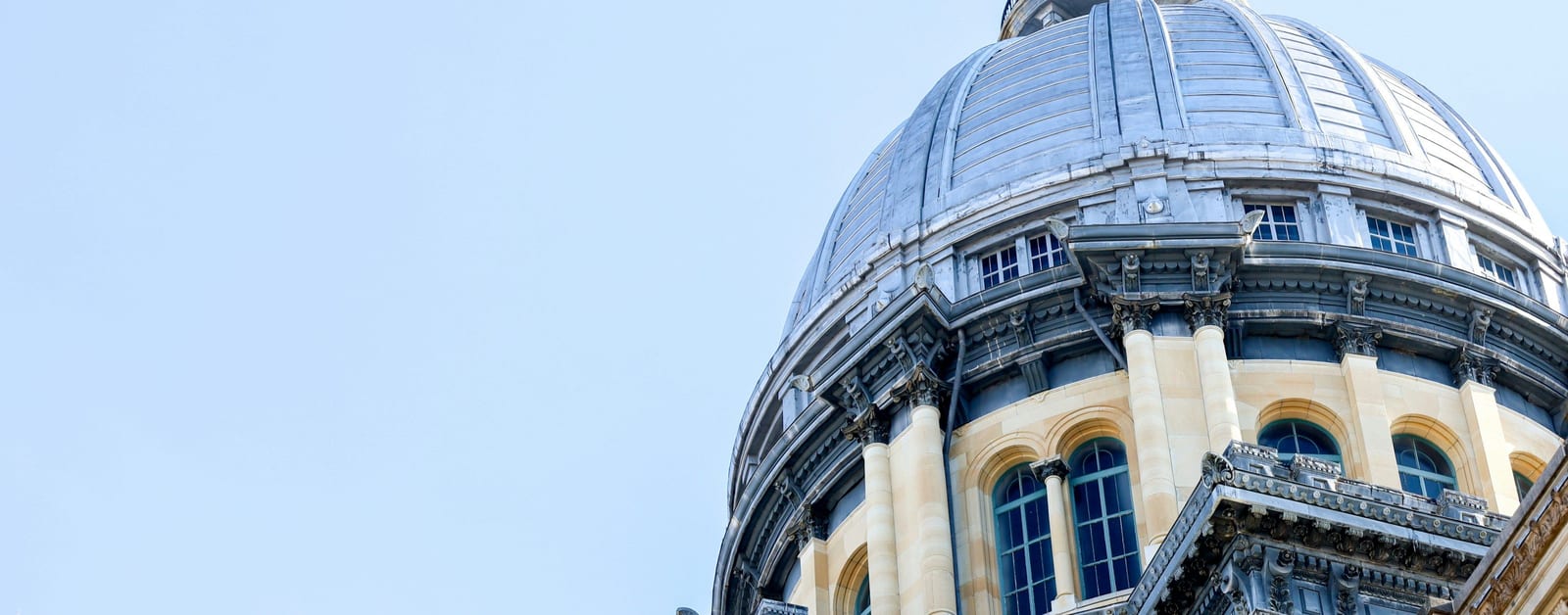 The dome of the Illinois State Capitol in Springfield against a pale blue sky