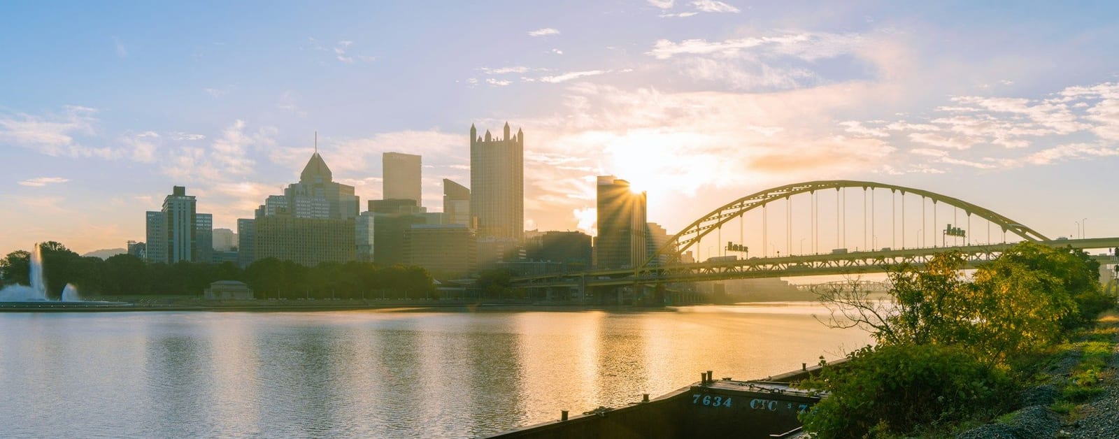 Downtown Pittsburgh skyline with PPG Place and the Fort Pitt Bridge at sunrise, seen across the river