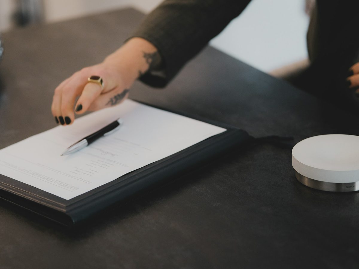 Hand with a pen over a written document on a clipboard