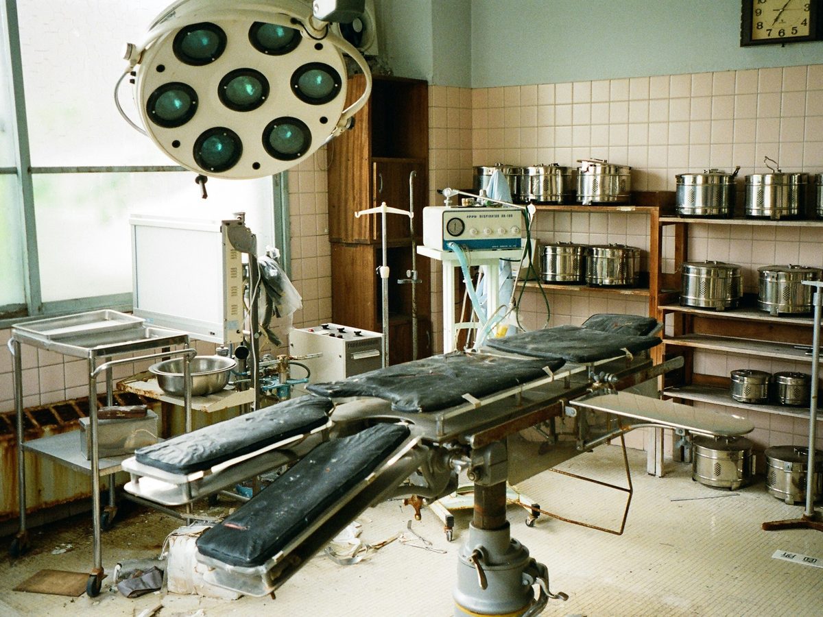 Operating room left with an old surgical table, light and equipment