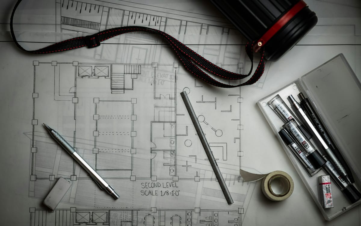 Architectural floor plans with drafting pencils, a scale ruler and tape