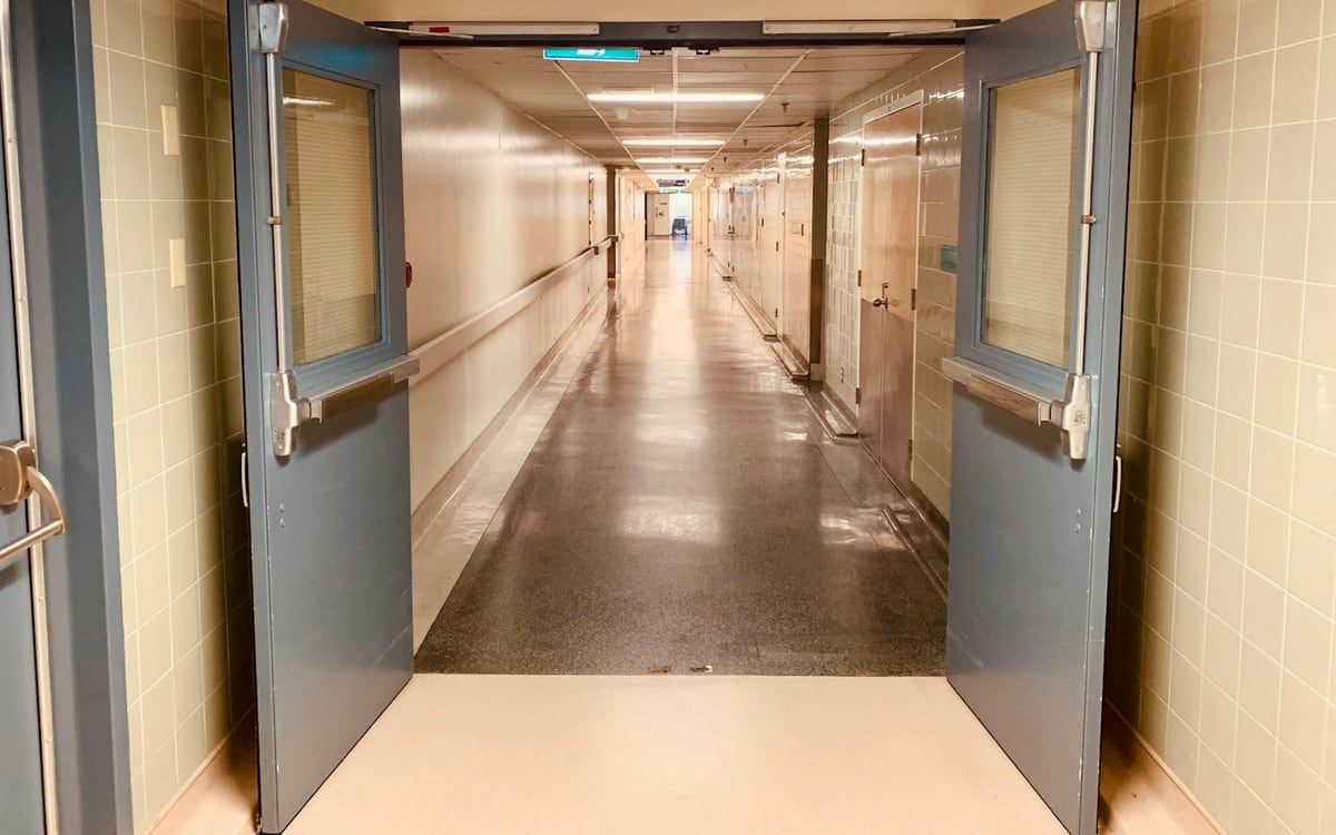 Open double doors onto a long, empty hospital corridor