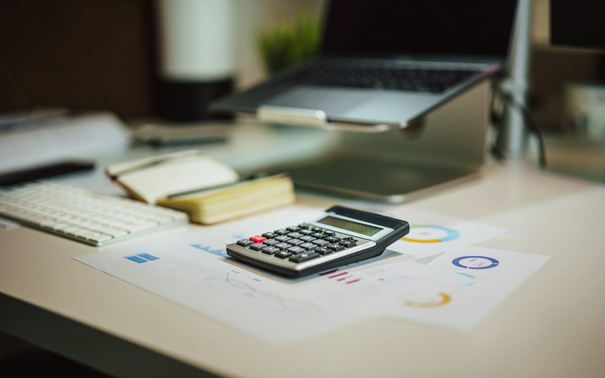 A calculator resting on printed financial reports on an office desk