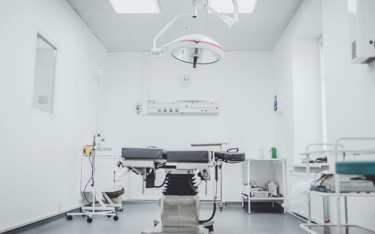 An empty operating room with a surgical table and overhead surgical light