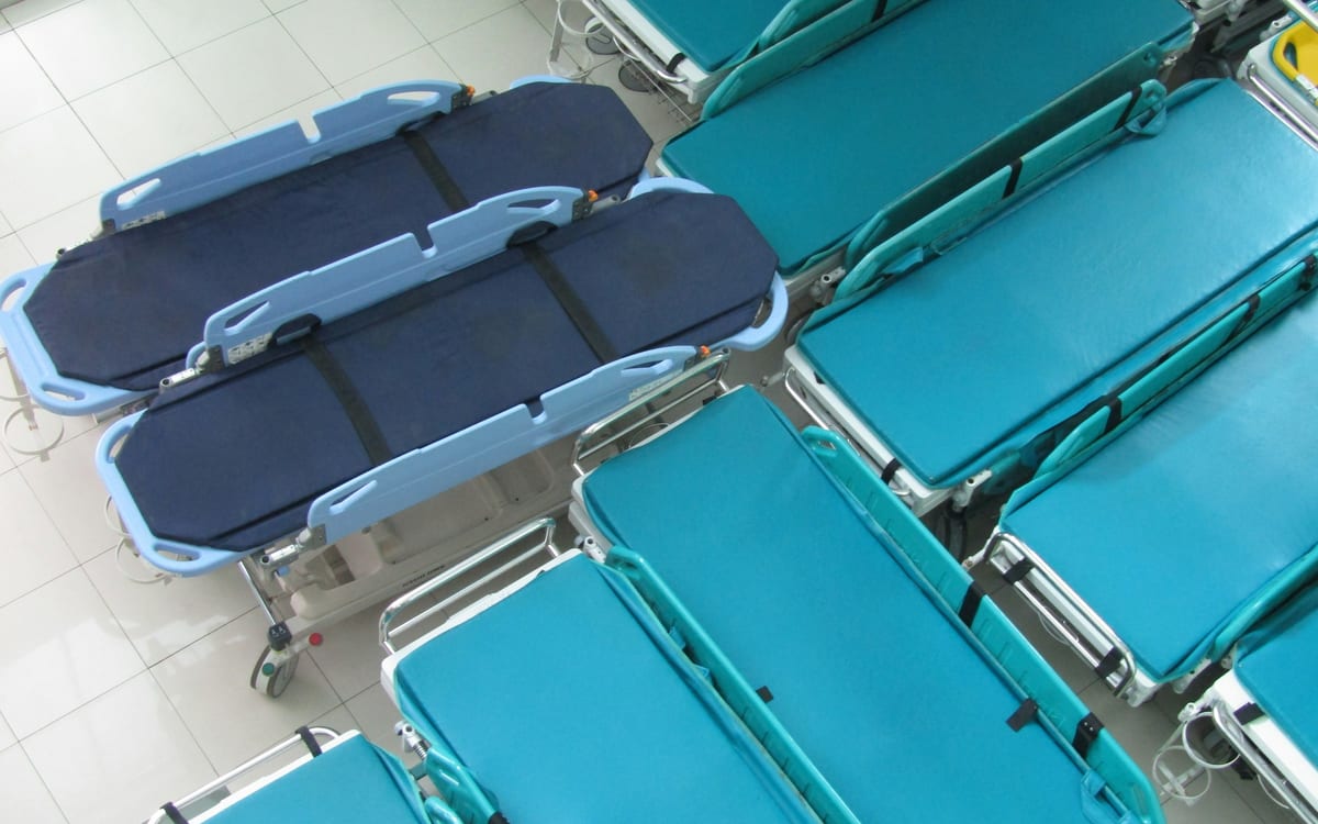 Surplus hospital stretchers lined up side by side in storage